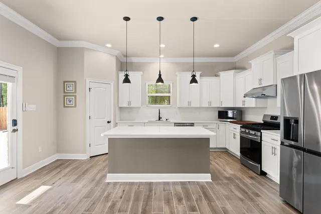 a large kitchen with stainless steel appliances granite countertop a sink a stove a refrigerator and island with wooden floor