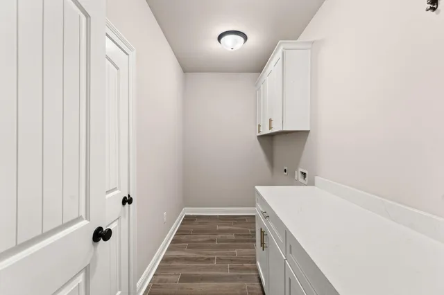 a view of a hallway with wooden floor and a bathroom