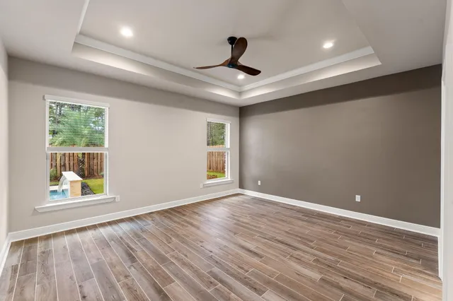 an empty room with wooden floor and a ceiling fan