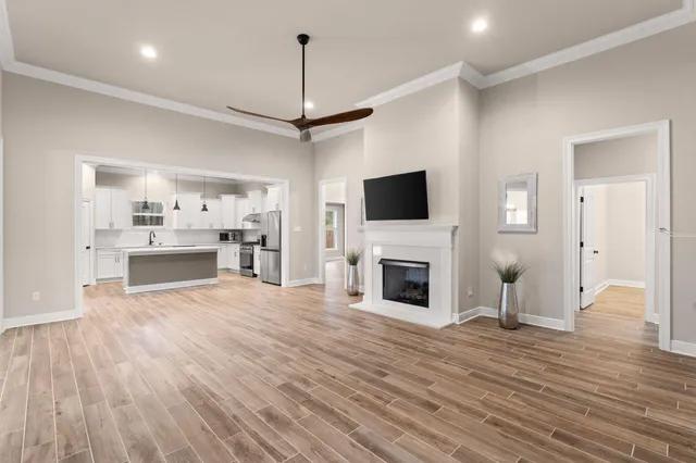 a view of a livingroom with a ceiling fan wooden floor and a ceiling fan