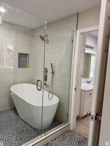 8965 Quail Run Drive Sandy, UT 84093 - Photo 45 of 56 Enclosed shower featuring a freestanding soaking tub, pebble tile flooring, glass shower enclosure, a built-in shower niche, and a fixed showerhead with a handheld sprayer