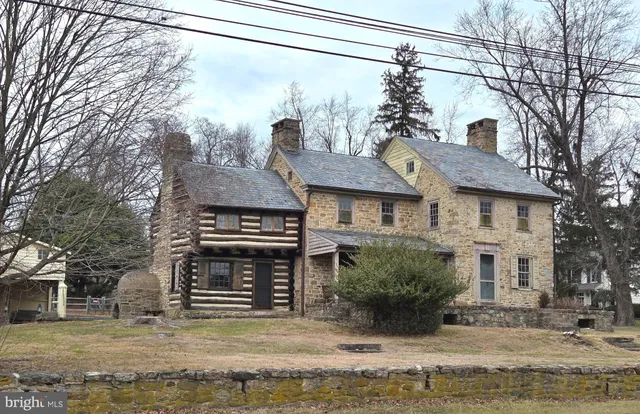 a front view of a house with a large tree