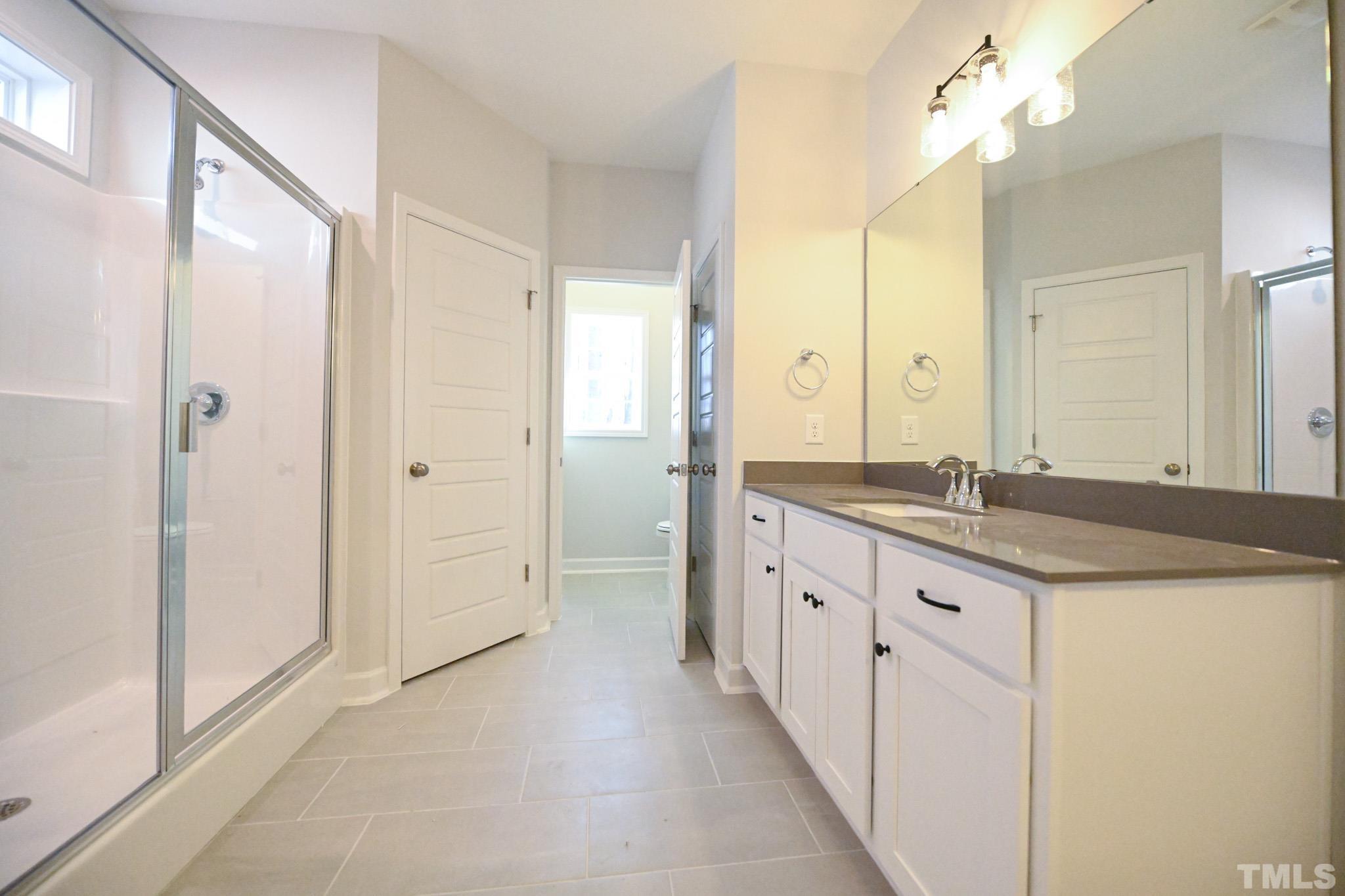 23 Chris Todd Way Angier, NC 27501 - Photo 19 of 28 a bathroom with a granite countertop sink a large mirror and a shower