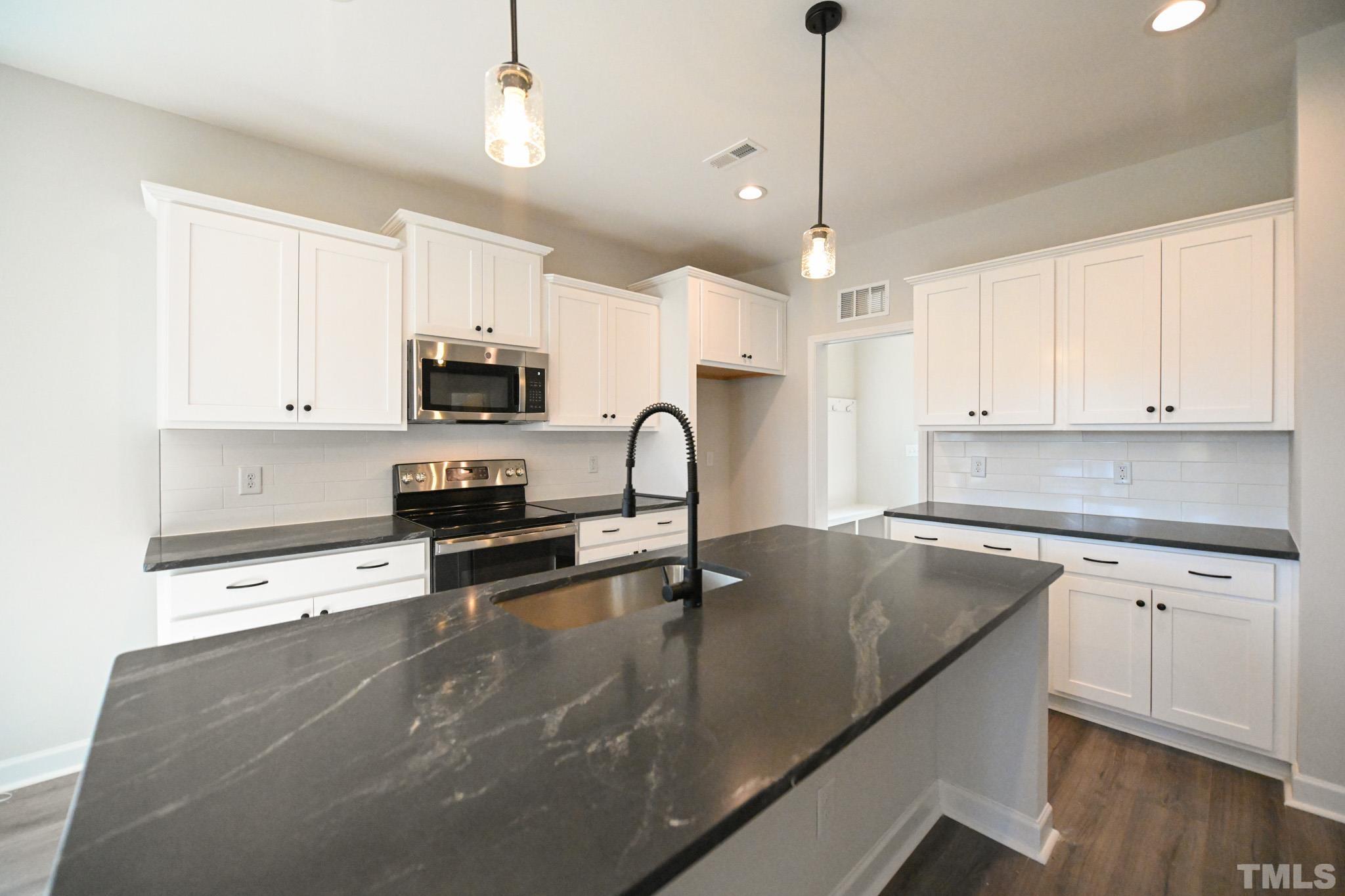 23 Chris Todd Way Angier, NC 27501 - Photo 8 of 28 a kitchen with granite countertop a sink stainless steel appliances and white cabinets
