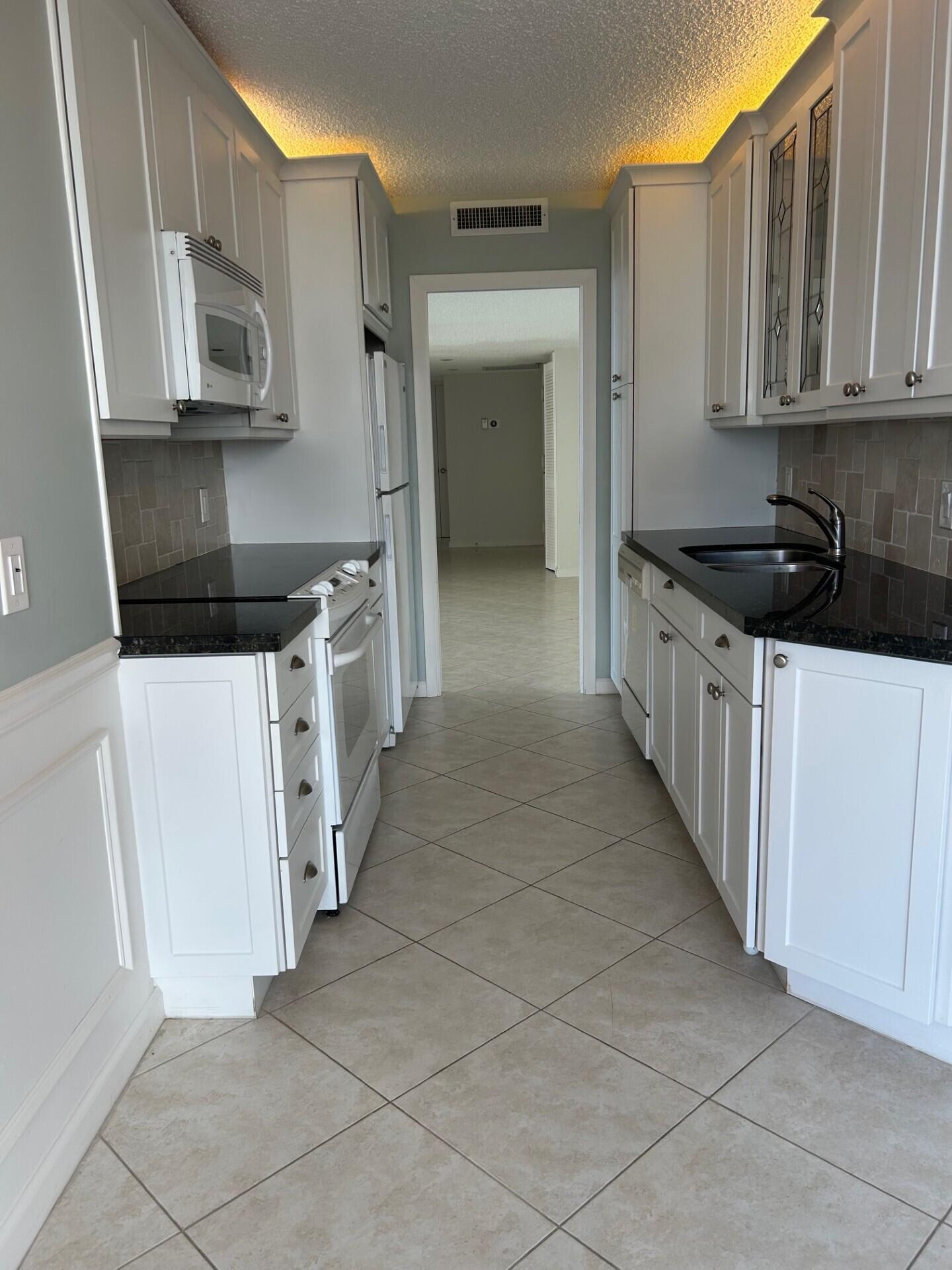 4200 North Ocean Drive, Unit 11405 Singer Island, FL 33404 - Photo 7 of 26 a kitchen with stainless steel appliances a stove a microwave a sink and cabinets