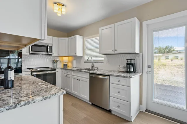 a kitchen with granite countertop a sink stainless steel appliances and cabinets