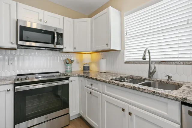 a kitchen with granite countertop a stove top oven microwave and cabinets