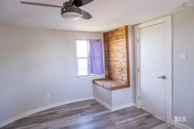 a view of an empty room with a window and wooden floor