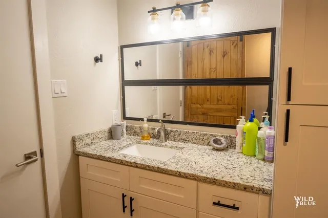 a bathroom with a granite countertop sink and a mirror