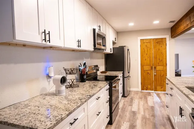 a kitchen with kitchen island granite countertop a sink appliances cabinets and a counter top space