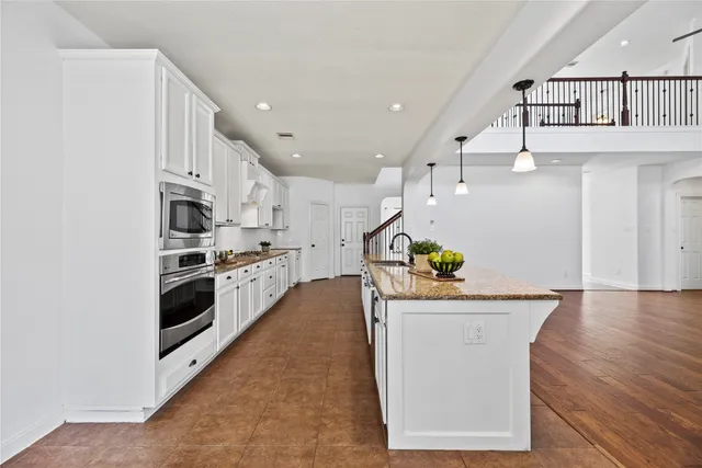 a kitchen with granite countertop a sink a counter top space and stainless steel appliances