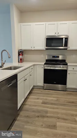a kitchen with stainless steel appliances a stove a sink and white cabinets