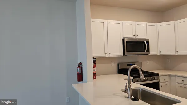 a kitchen with stainless steel appliances a sink a stove a microwave a sink and cabinets