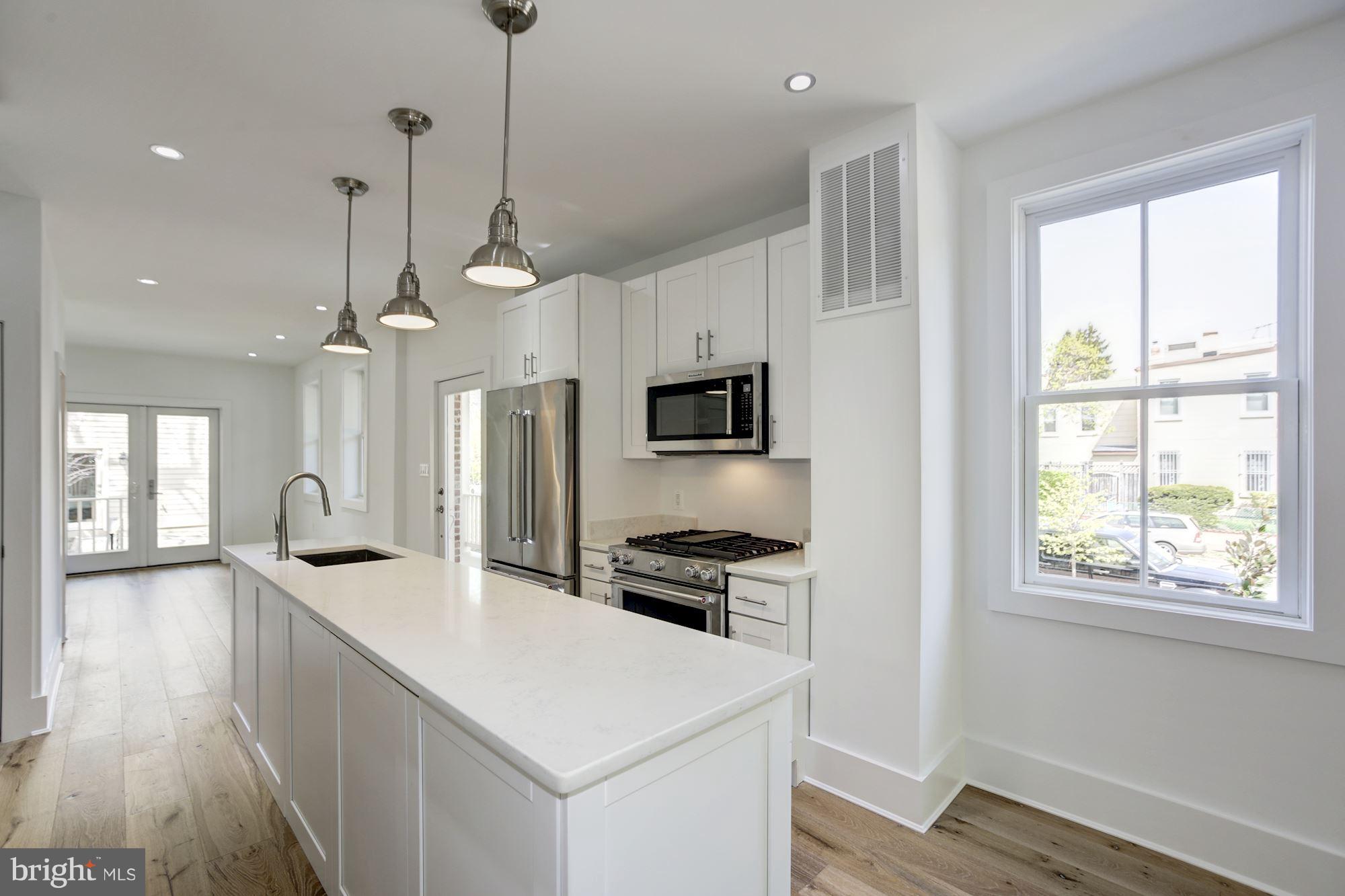 401 11th Street Southeast Washington, DC 20003 - Photo 11 of 27 a kitchen with stainless steel appliances kitchen island a white counter space a sink and a window