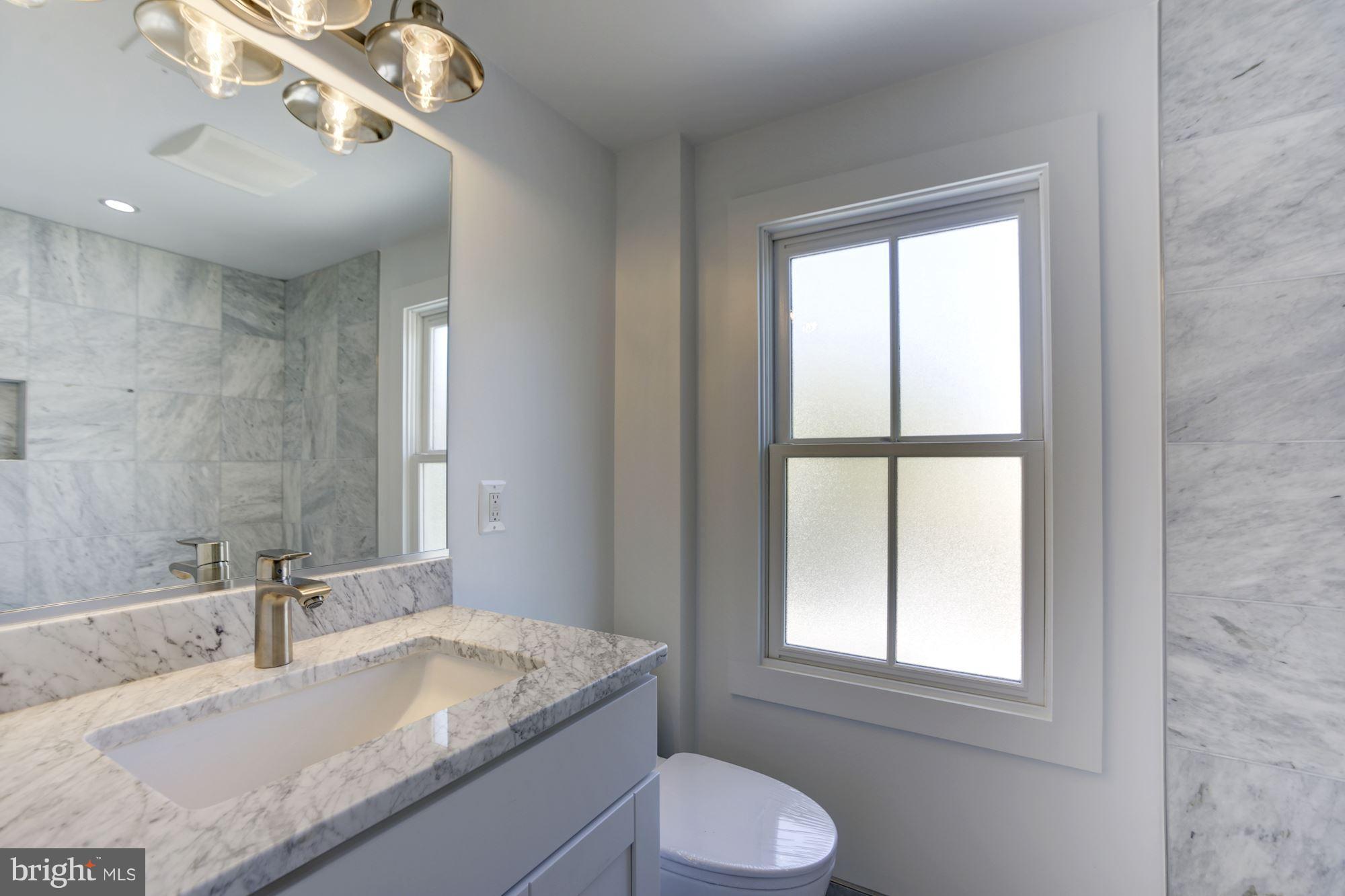 401 11th Street Southeast Washington, DC 20003 - Photo 19 of 27 a bathroom with a granite countertop sink a toilet and mirror