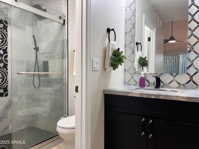 a bathroom with a granite countertop sink a toilet and shower