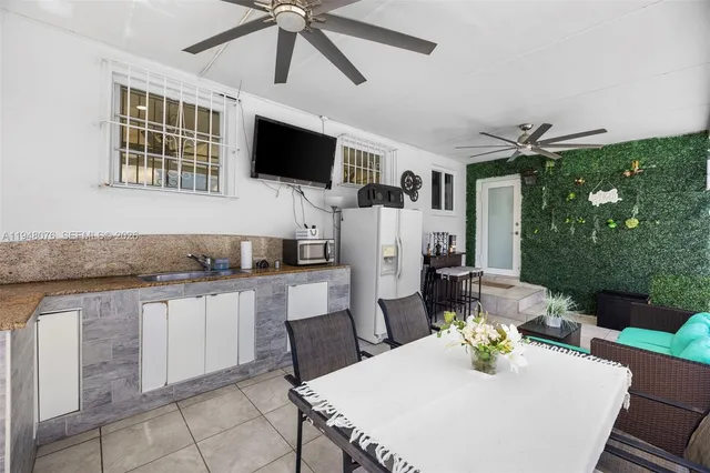 a living room with stainless steel appliances kitchen island granite countertop a table chairs microwave and sink