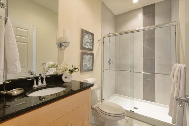 a bathroom with a granite countertop sink a toilet and shower