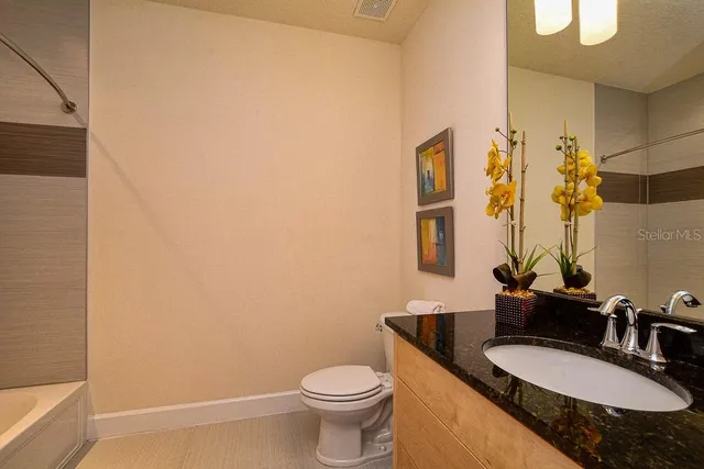 a bathroom with a granite countertop sink and a mirror with toilet