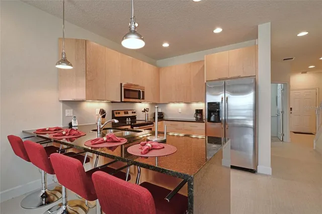 a kitchen with a refrigerator a stove a sink dishwasher a dining table and chairs with wooden floor