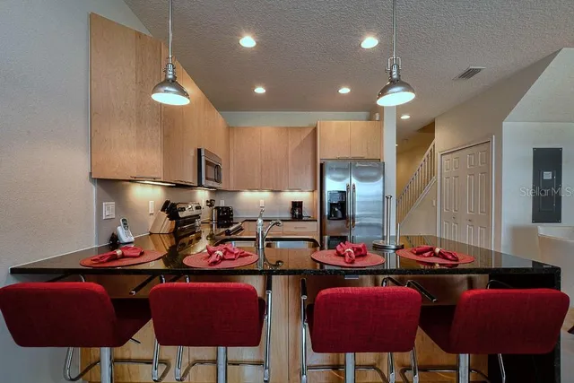 a kitchen with stainless steel appliances granite countertop a sink white cabinets dining table and chairs