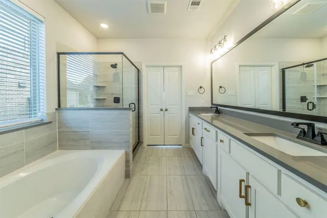 a large spacious bathroom with a tub sink shower and mirror