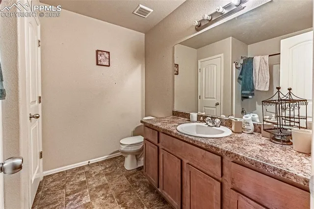 a bathroom with a granite countertop sink toilet and mirror