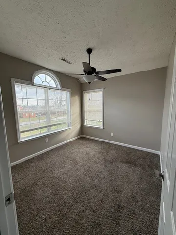 en empty room with windows and ceiling fan