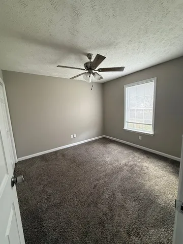 an empty room with windows and fan