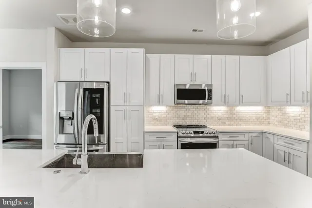 a kitchen with granite countertop a refrigerator and a stove top oven