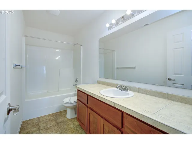 a bathroom with a granite countertop sink a toilet a mirror and bathtub