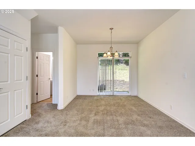 a view of an empty room with window and chandelier fan