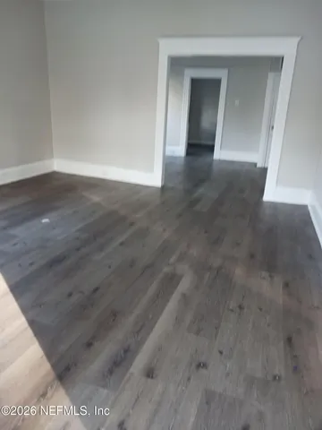 a view of an empty room with wooden floor and closet