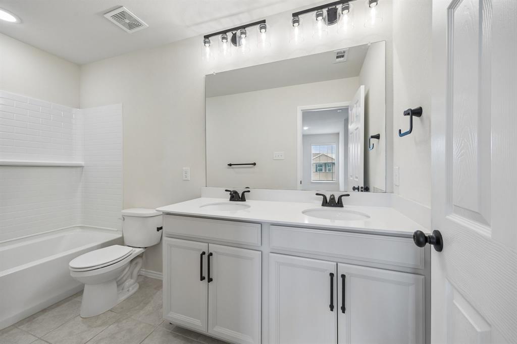 1006 Voca Dr. Forney, TX 75126 - Photo 23 of 26 a bathroom with a toilet a sink a mirror and vanity