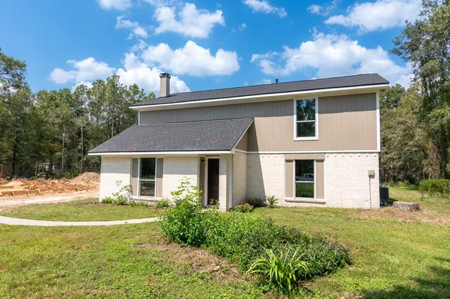 a front view of house with yard and trees in the background