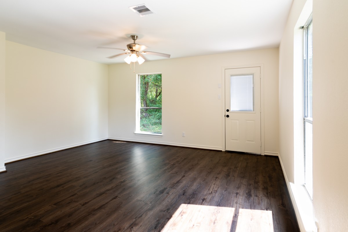 13087 Crystal Trail Conroe, TX 77306 - Photo 31 of 47 an empty room with wooden floor chandelier fan and windows