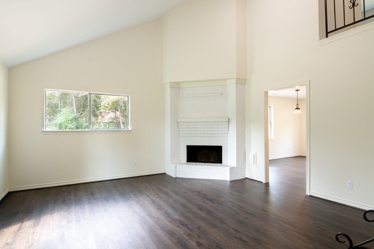 13087 Crystal Trail Conroe, TX 77306 - Photo 46 of 47 an empty room with wooden floor a fireplace and windows