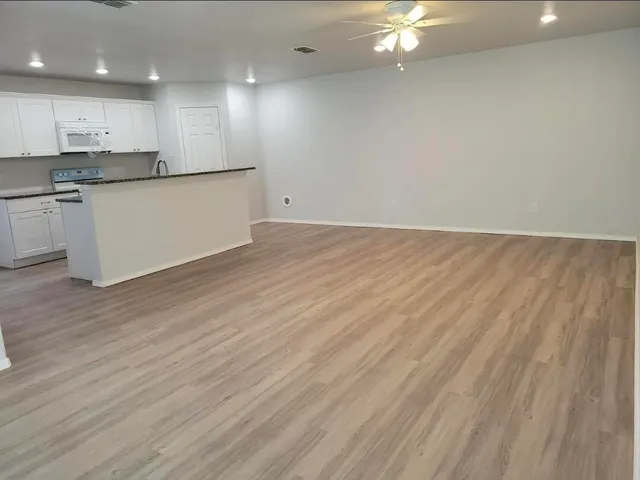 a large kitchen with granite countertop a large counter top and stainless steel appliances