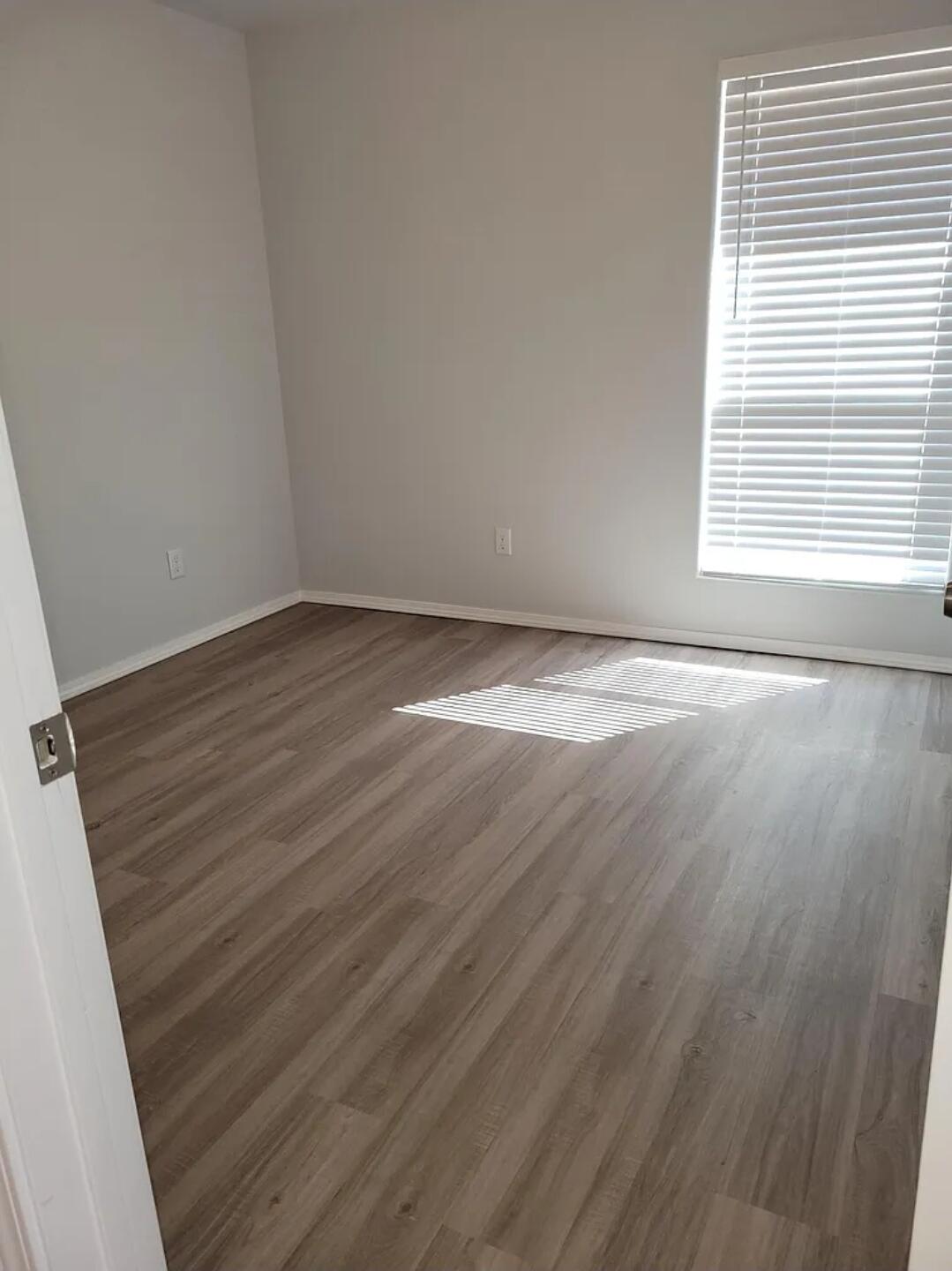 5524 Jarvis Street, Unit B Lubbock, TX 79416 - Photo 7 of 13 a view of an empty room with wooden floor and a window
