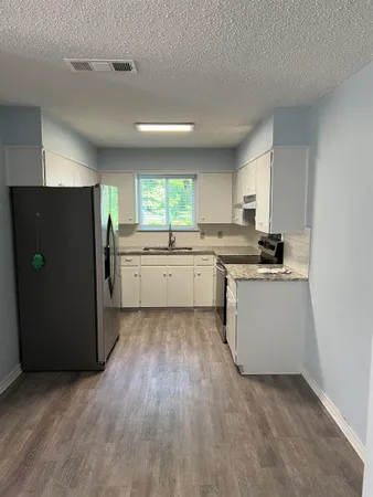 a kitchen with a refrigerator and white cabinets