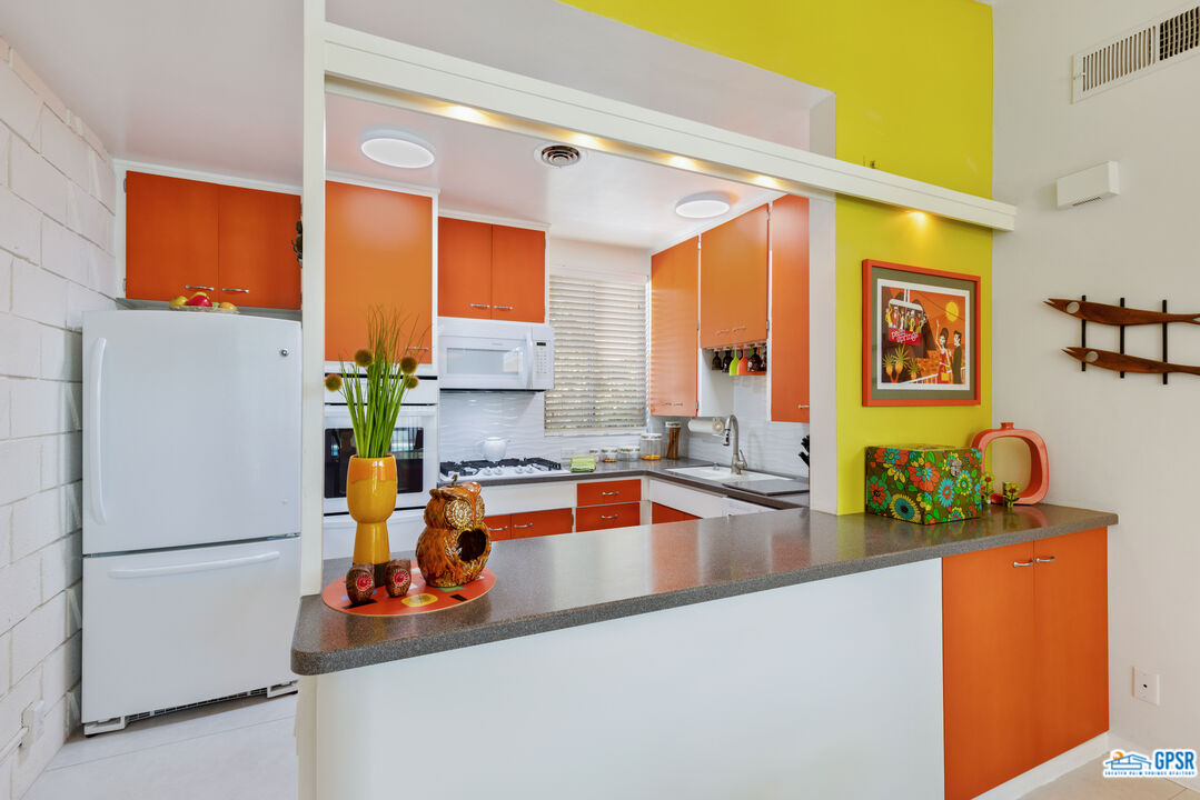 1655 Andee Drive Palm Springs, CA 92264 - Photo 6 of 23 a kitchen with stainless steel appliances granite countertop a refrigerator a stove and a sink with wooden floor