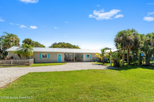 a view of a house with a yard and palm trees