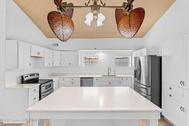 a view of a room with a chandelier fan and kitchen view