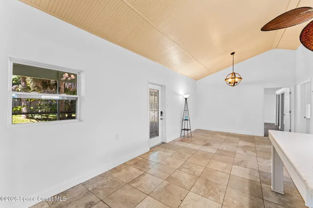 a view of an empty room with wooden floor and a ceiling fan