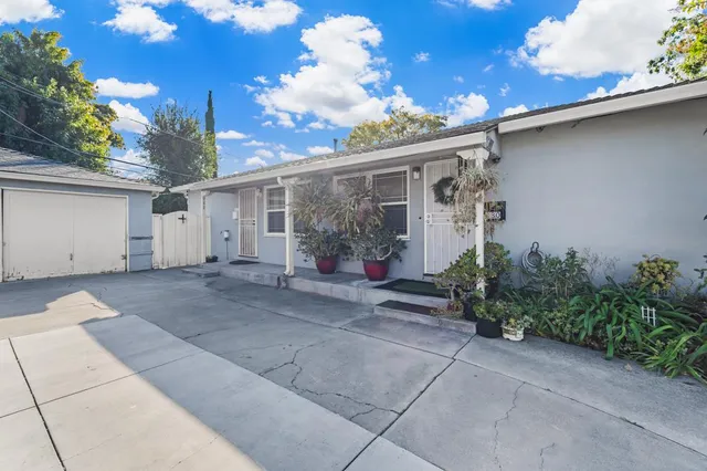 a view of a house with a yard and potted plants