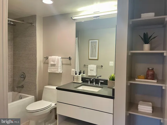 a bathroom with a granite countertop sink a toilet a mirror and shower