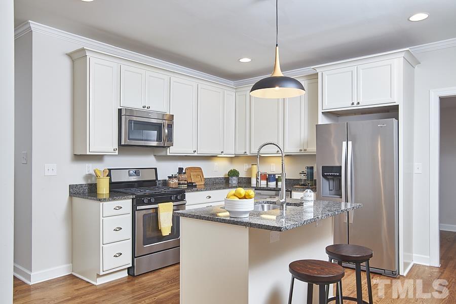 2203 Chapel Hill Road Durham, NC 27707 - Photo 15 of 37 a kitchen with stainless steel appliances granite countertop a refrigerator a stove a sink dishwasher and white cabinets with wooden floor