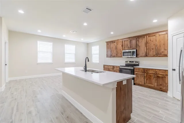 a large kitchen with stainless steel appliances granite countertop a stove a sink a refrigerator a microwave and cabinets