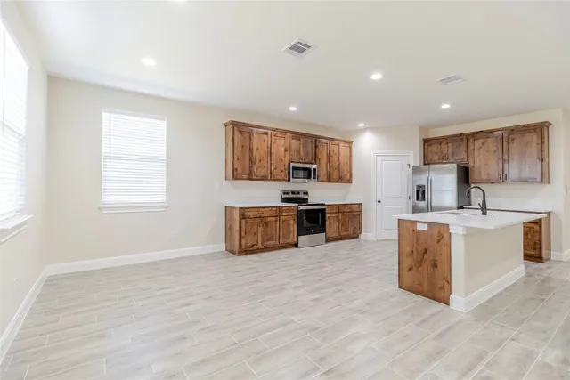 a large kitchen with a wooden floor and stainless steel appliances