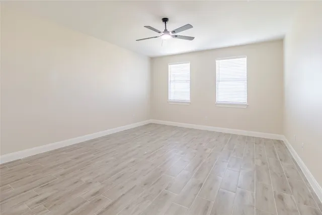 an empty room with wooden floor ceiling fan and window